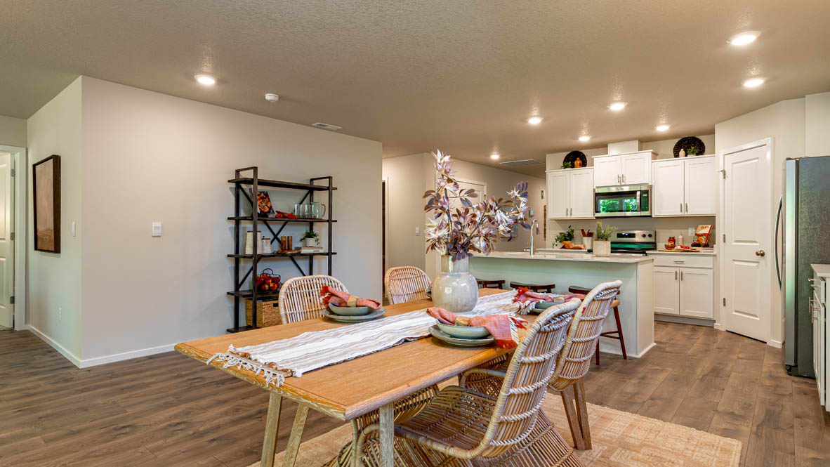 Eden Estates dining room with laminate flooring, windows, and the kitchen in the background