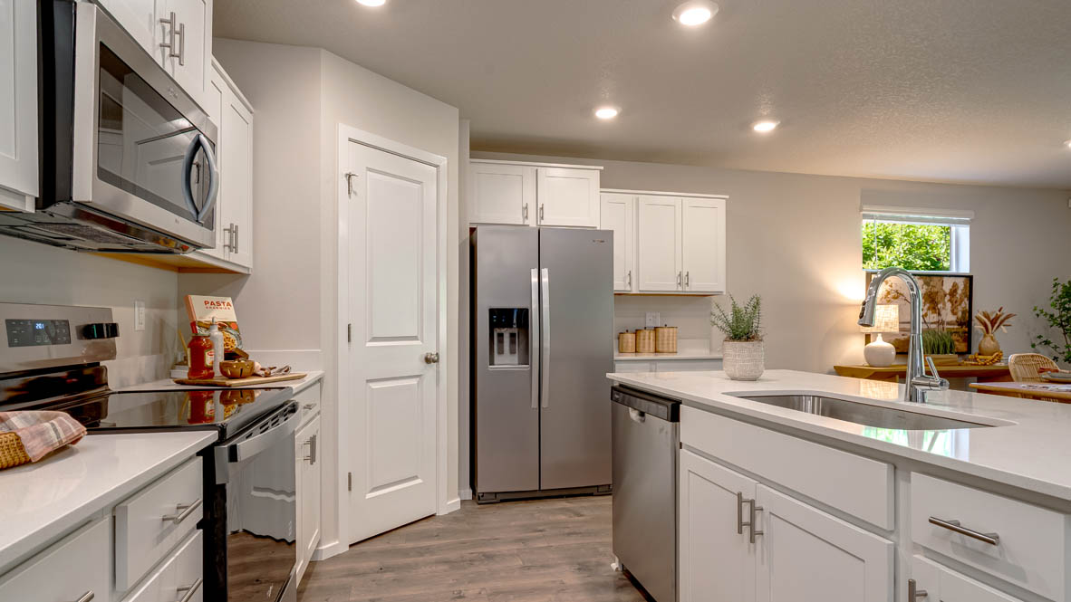 Eden Estates kitchen with laminate flooring, stainless steel appliances, cabinets, window, solid surface countertops