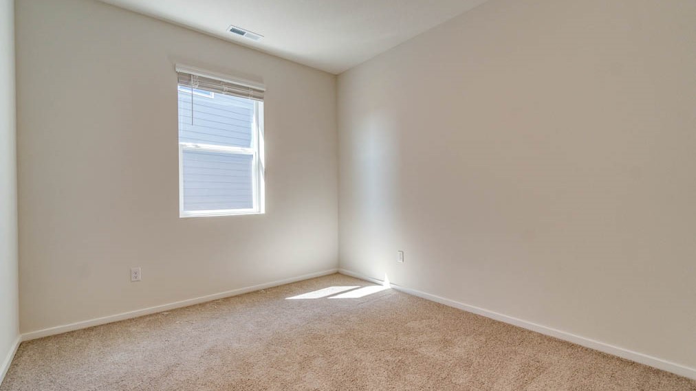 Eden Estates bedroom with carpet, window, and white walls