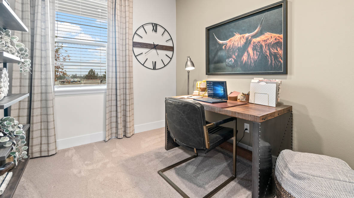 Sorrento Estates Carpeted den with highland cow art print, desk set up, and shelves