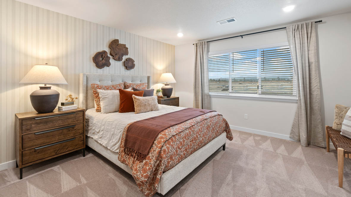 Sorrento Estates Primary bedroom with carpeting, wall paper, a dark wood dresser on either side of the bed, three windows, and burnt orange accent pieces.