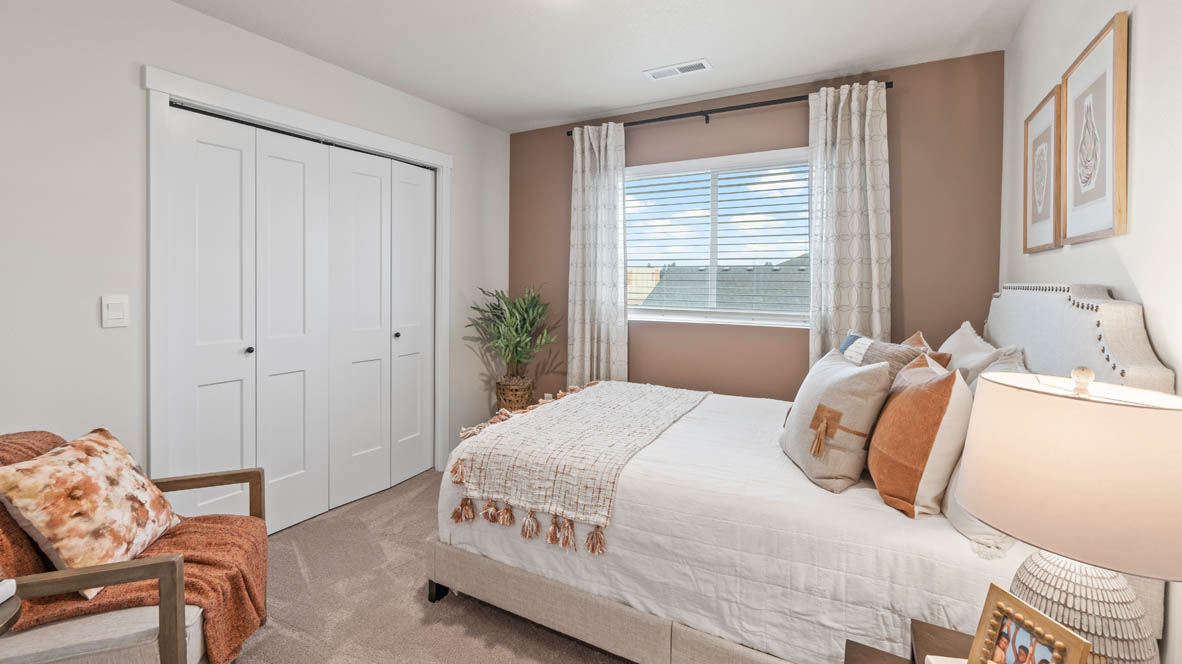 Sorrento Estates Bedroom with accent wall, white bedding, white closet doors, carpeting, and side table with lamp