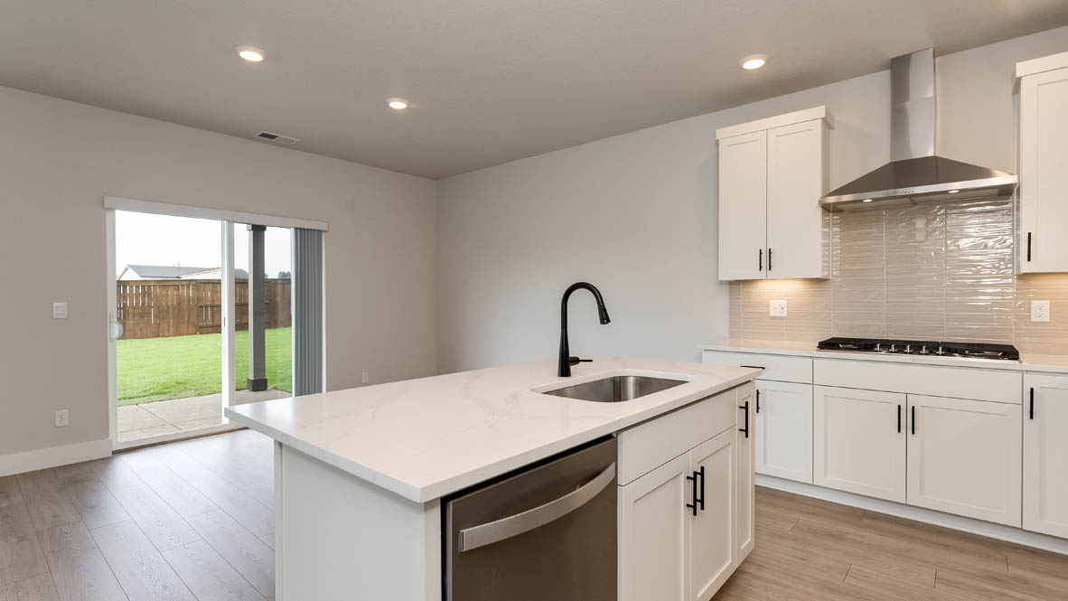 Sorrento Estates kitchen with white solid surface countertops and white shaker style cabinets and full height tile backsplash with hood vent and stainless steel appliances