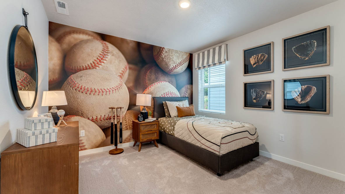 Sorrento Estates Bedroom with baseball theme, the top half of the walls are white and the bottom half are a light blue-gray color, metal rod bed frame, carpeting, and a wooden dresser
