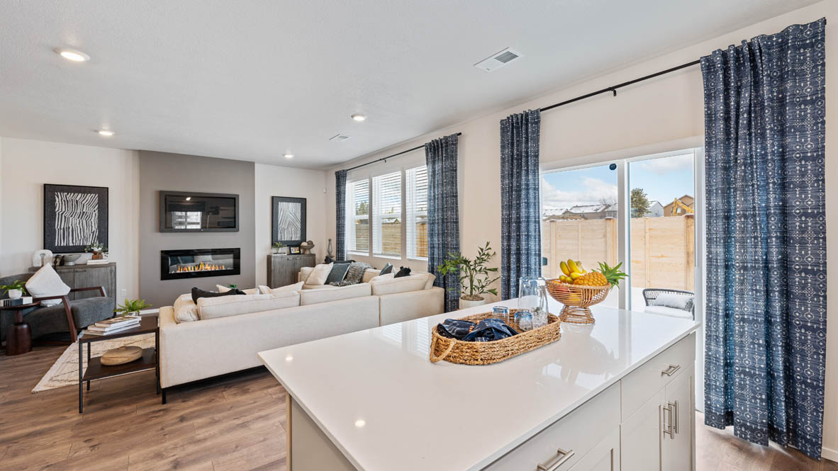 Monrovia Kitchen with island that has white quartz countertops, two seats set up at the island, stainless steel appliances, a sliding glass door to the backyard, and white shaker style cabinets