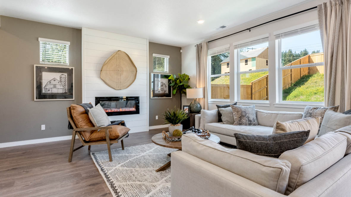 Sorrento Estates Great room with large sectional couch over a rug and surrounding a coffee table facing the fire place