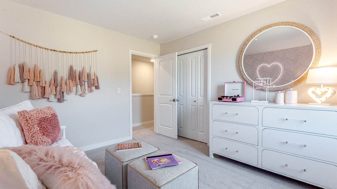 Sorrento Estates Pink themed bedroom with a white dresser and round mirror