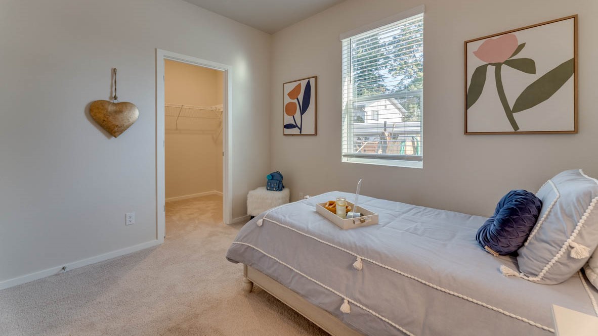 Sorrento Estates bedroom with a bed, carpet, paintings, nightstand with a lamp, dresser with a lamp