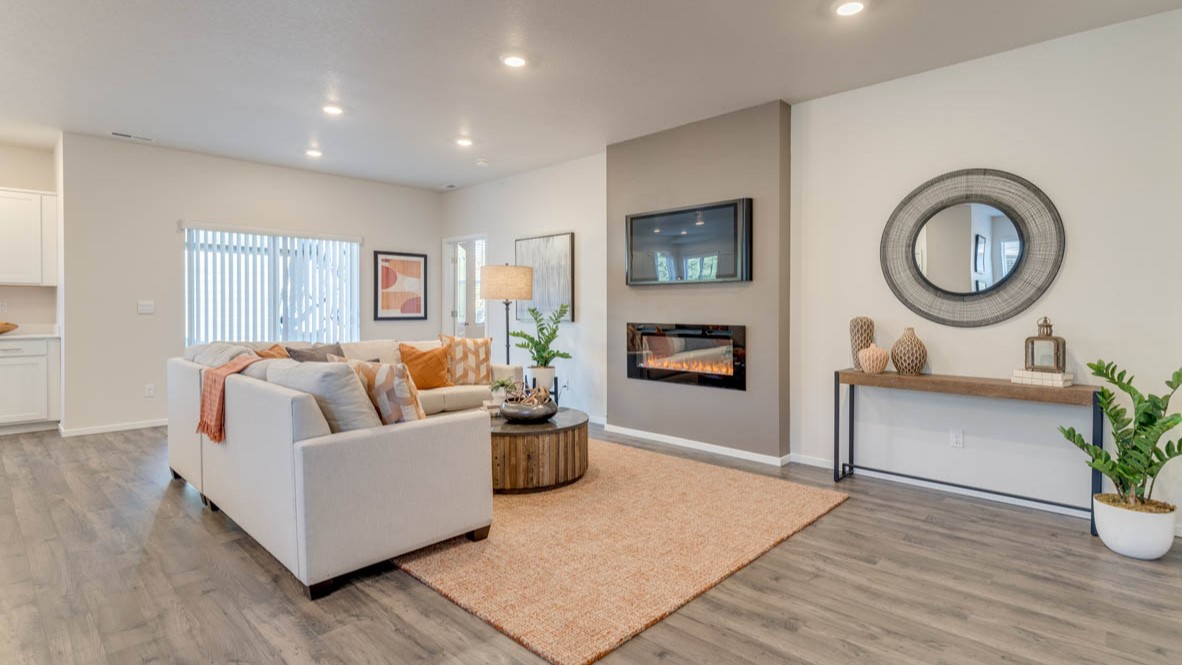 Sorrento Estates living room with a fireplace, carpet, white couch, circle mirror, and a side table