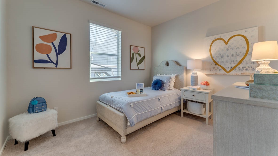 Sorrento Estates bedroom with a bed, carpet, paintings, nightstand with a lamp, dresser with a lamp