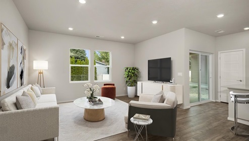 Living area with large white rug, a white couch with matching white accent chair, a television mounted on the right wall above a white tv console, abstract art on the left wall next to a door leading to a bedroom, and two large windows letting in natural light.