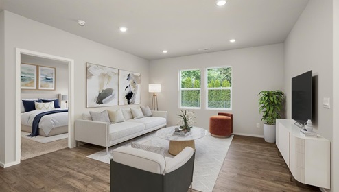 Living area with large white rug, a white couch with matching white accent chair, a television mounted on the right wall above a white tv console, abstract art on the left wall next to a door leading to a bedroom, and two large windows letting in natural light.