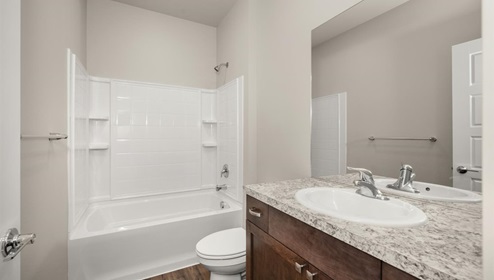 A bathroom with dark cabinets and light patterned counters.