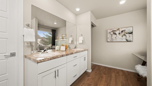 A bathroom with white cabinets and beige counters.