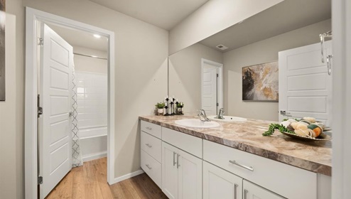 A bathroom with white cabinets and beige counters.