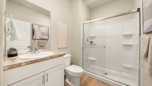 A bathroom with white cabinets and beige counters.