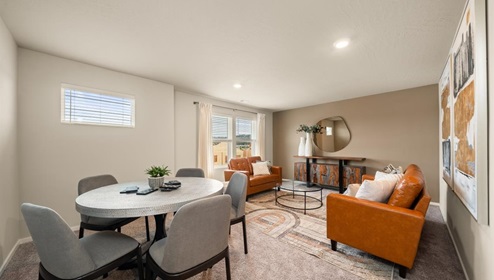 A room with a table and couches with multiple windows letting in natural light.