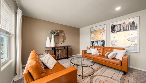 A room with a table and couches with multiple windows letting in natural light.