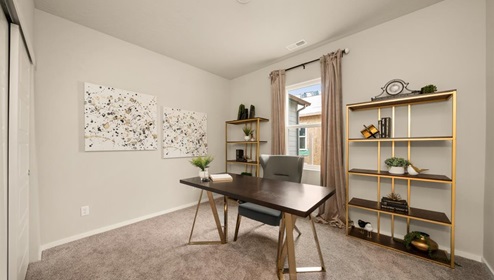 A room with a desk and shelves on the wall. There's a window letting in natural light.