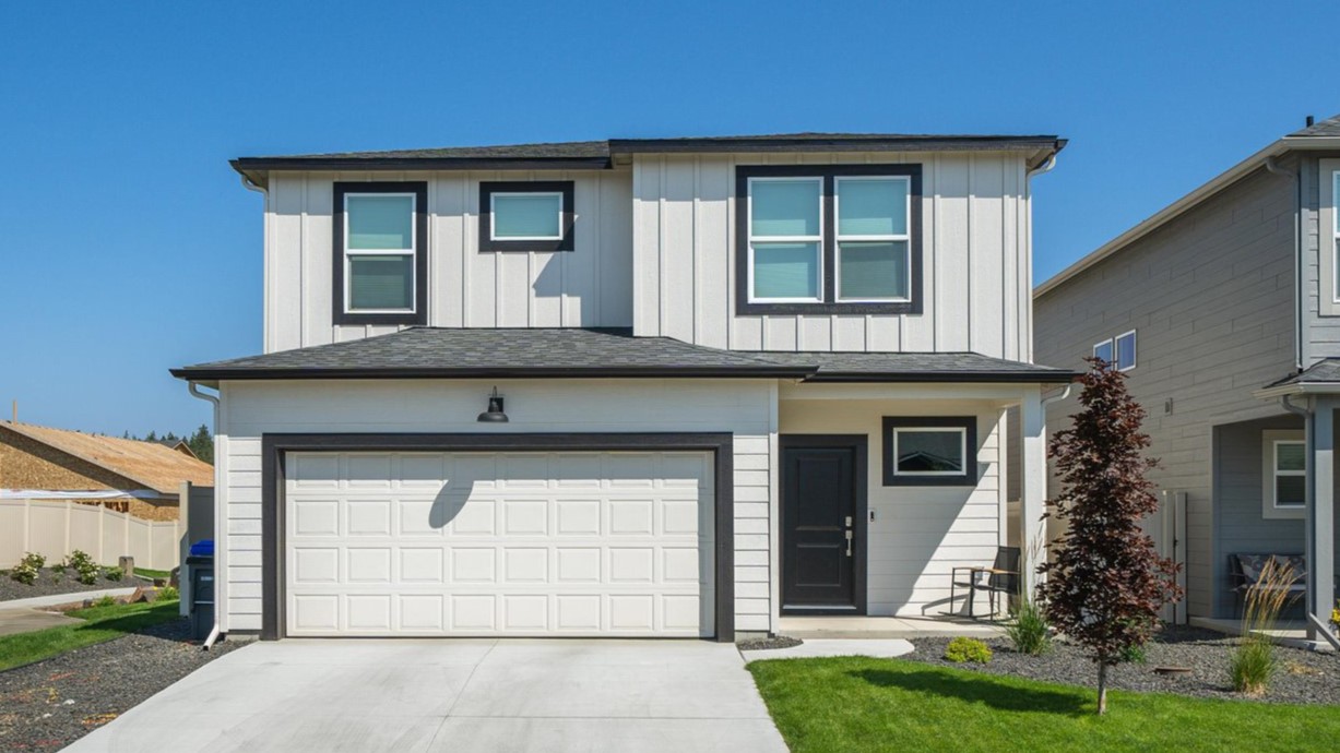 Photo of a two story home with white siding and dark accents and a dark roof.