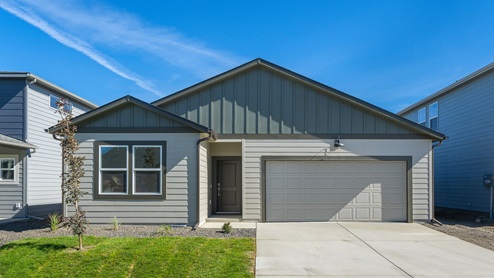 Photo of a one story house, the house has two toned off white and light grey siding and grey accents with a dark roof.