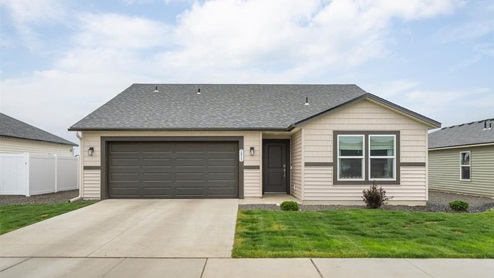 Photo of a one story house, the house has tan siding and brown accents with a dark roof.