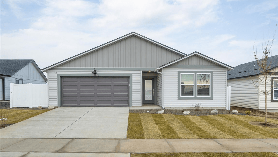 Photo of a one story house, the house has two toned off white and light grey siding and grey accents with a dark roof.