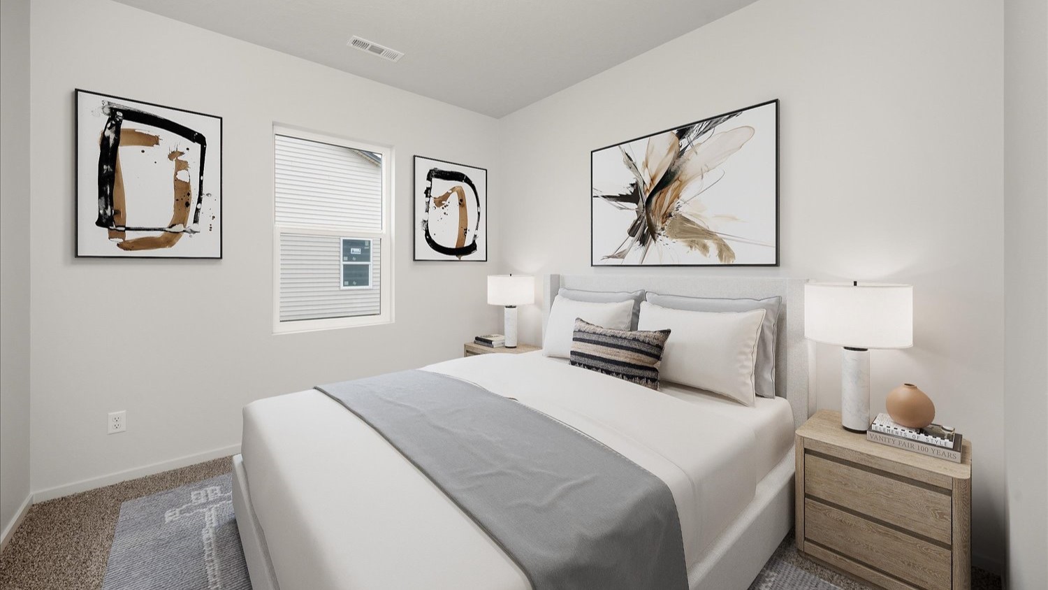 A bedroom with a bed with white sheets and decorative pillows and two bedside tables featuring lamps. Multiple abstract paintings are hung on the walls and there is one window letting in natural light.