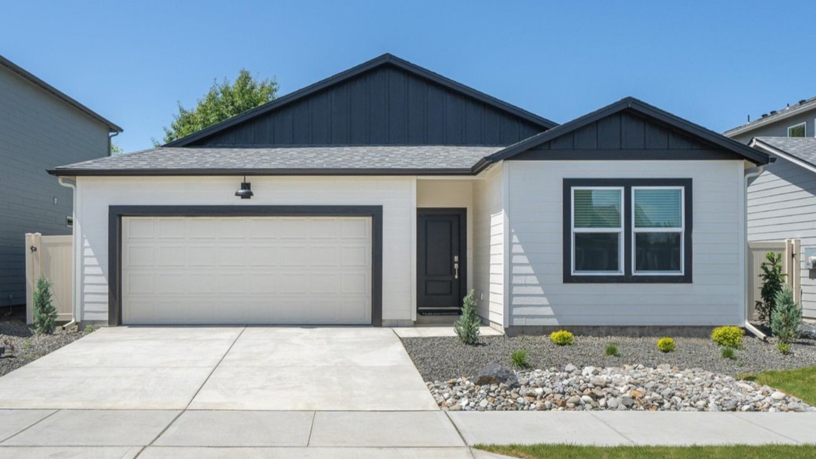 Photo of a one story home with two toned white and black siding and dark accents and a dark roof.
