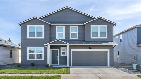 Photo of a two story home with dark grey siding, light accents, and a dark roof.