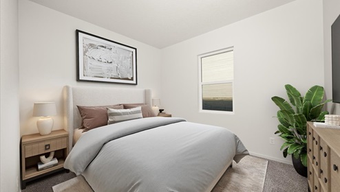 A bedroom with a bed with grey sheets and two side tables with lamps. There's abstract art on the wall and a window.