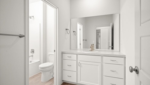 A bathroom with white cabinets and countertops.