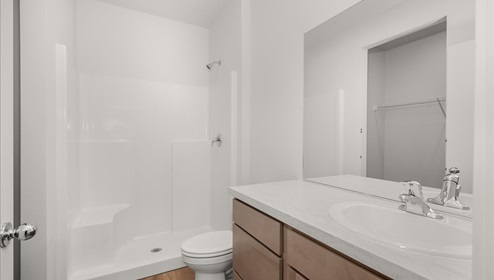 A bathroom with brown wood cabinets and white counters.