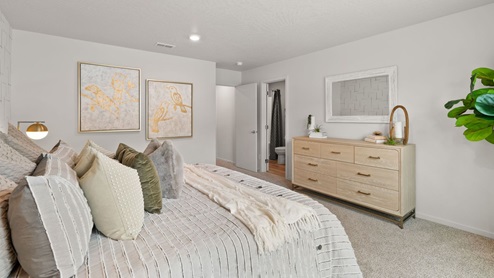 A large bedroom with a bed with grey sheets and decorative pillows.