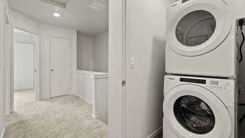 A laundry room with a stacked washer and dryer.