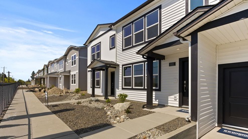 A row of townhomes with white siding and black accents.