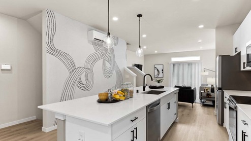 Behind expansive kitchen island at Cathcart Crossing model home with wall artwork and living room in background