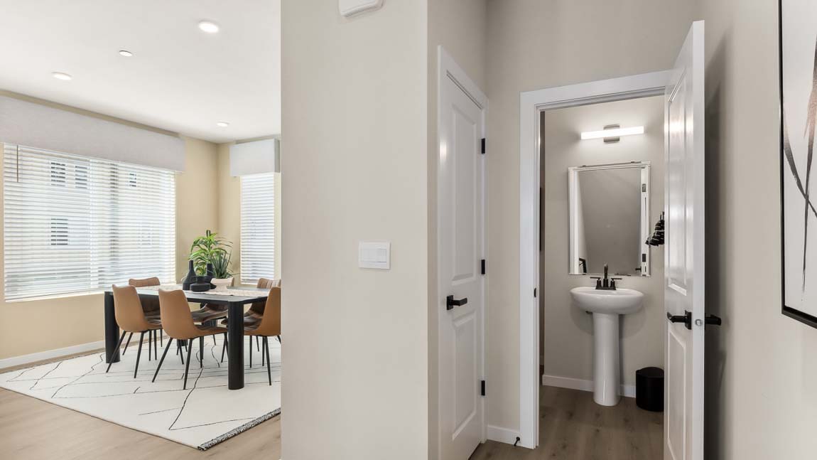 Hallway view of dining room in background with powder room that provides a pedestal sink, mirror, and modern light fixture