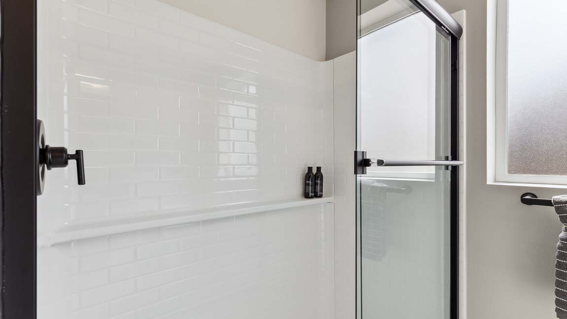 Private bathroom with quartz double-sink vanity, spacious step-in shower, with additional light provided by the large window