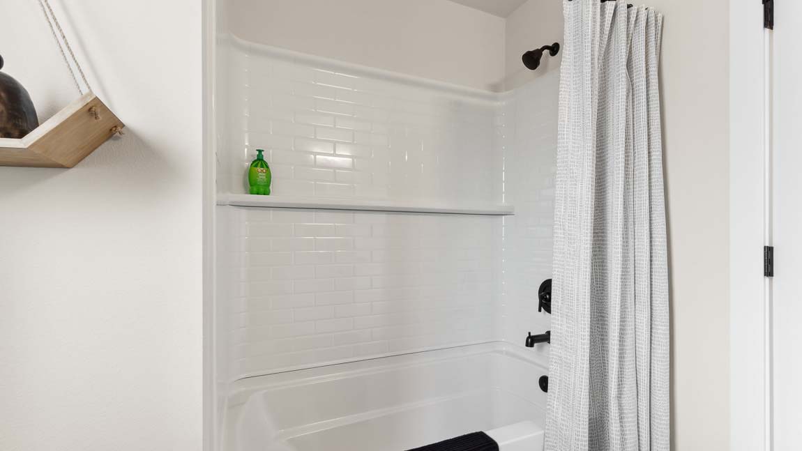 Built-in tub-shower combo in the hallway bathroom featured in the Addison home design at Cathcart Crossing