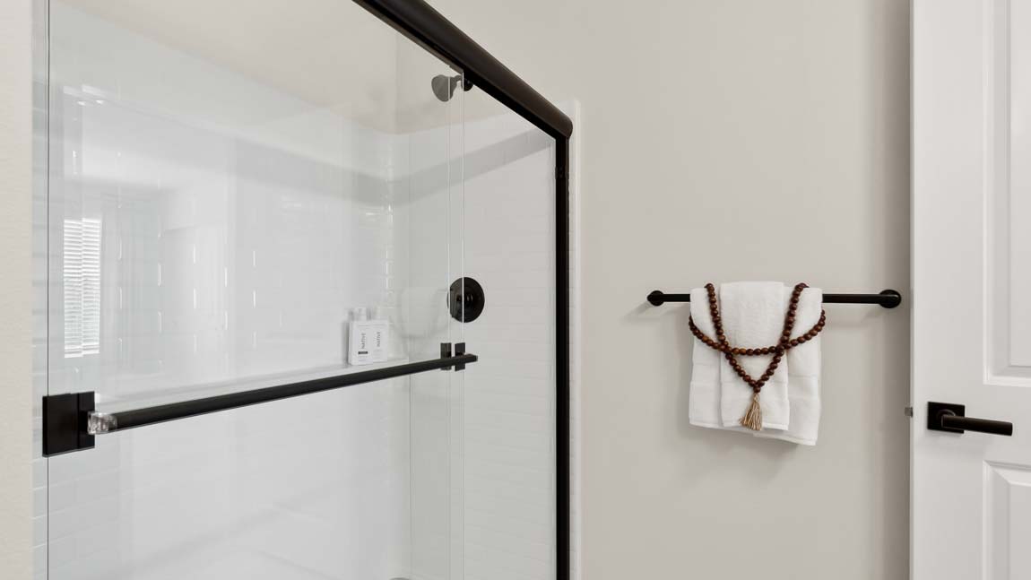 Closer view of the Bennett private upstairs bathroom step-in shower with glass sliding doors and built-in shelf