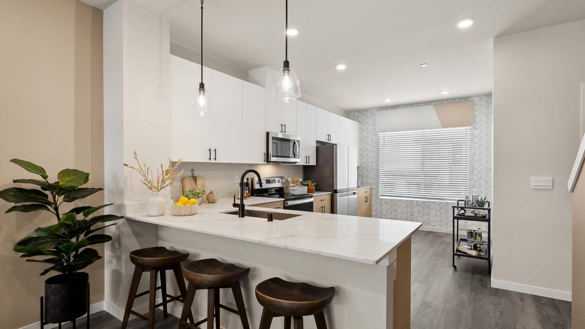 Bennett model home kitchen peninsula with white cabinetry, stainless steel appliances, and two pendant lights