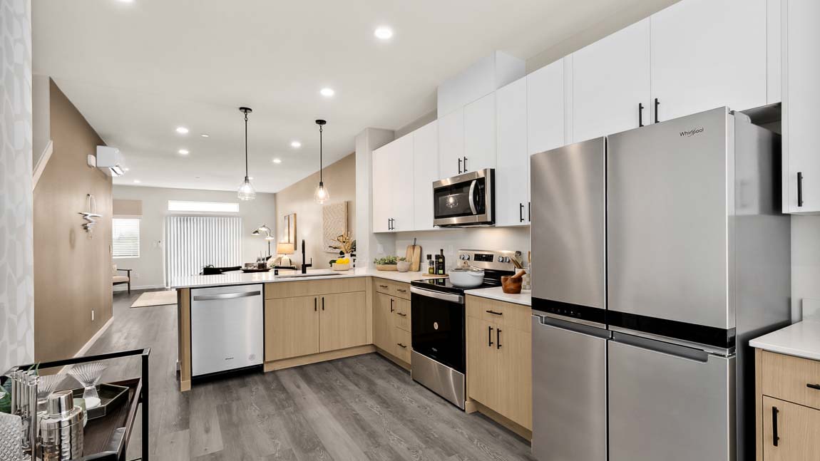 Stainless steel appliances featured in model home kitchen with dual-color cabinetry, and peninsula