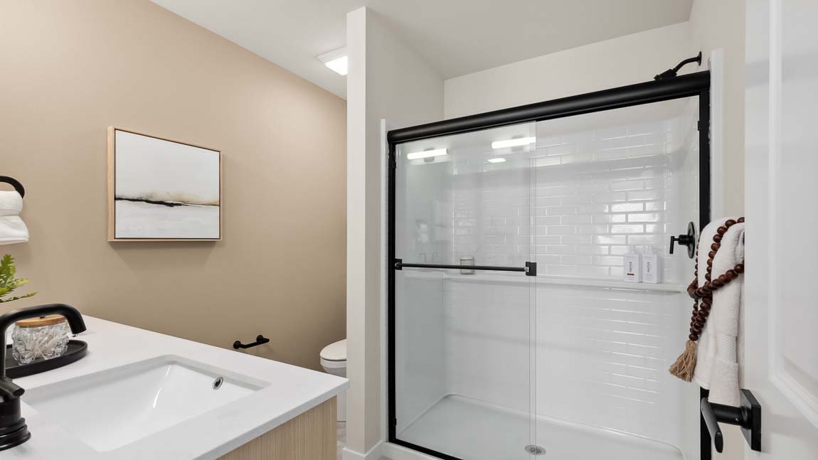 Closer view of the Bennett private upstairs bathroom step-in shower with glass sliding doors and built-in shelf