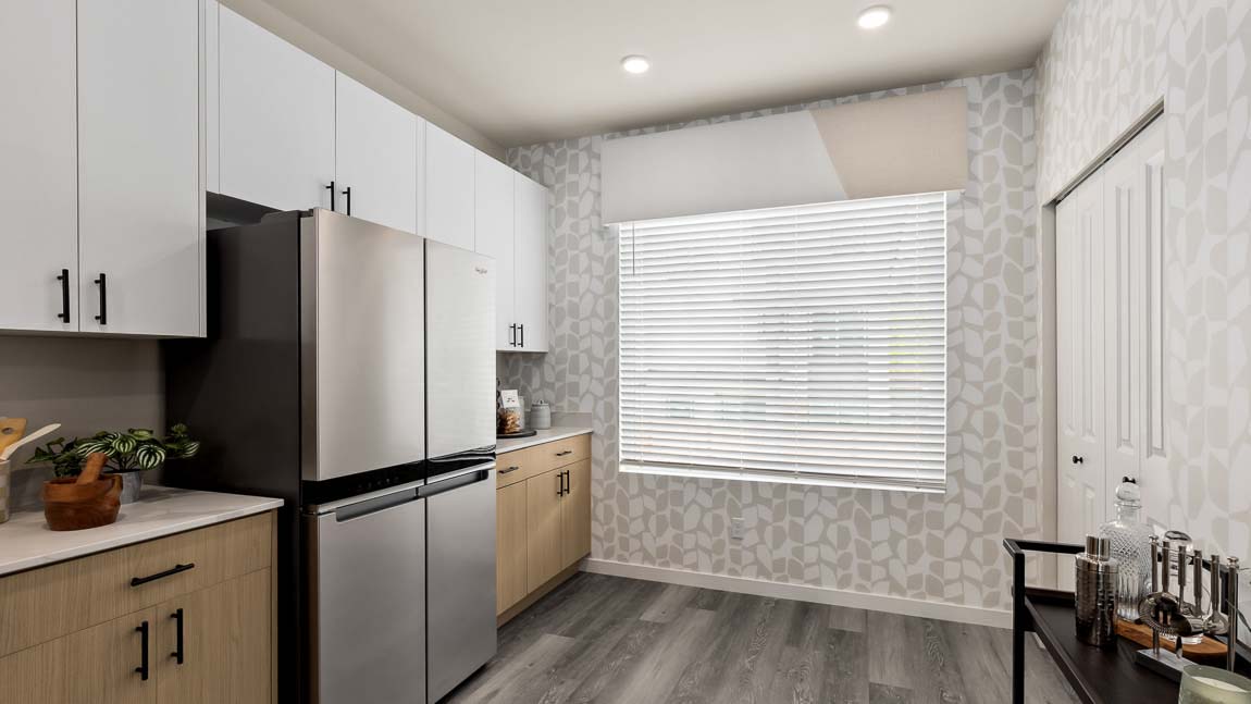 Bennett home kitchen features a bright window, dual-color cabinetry, stainless steel appliances, and quartz countertops