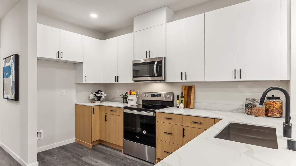 Capri model home kitchen features dual-color white and natural wood cabinetry and stainless steel appliances