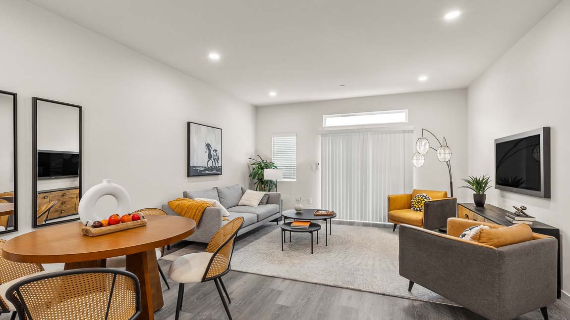 Wide angle view of Capri model home dining area and living room featuring glass sliding door access to balcony, with a transom above and a corner window