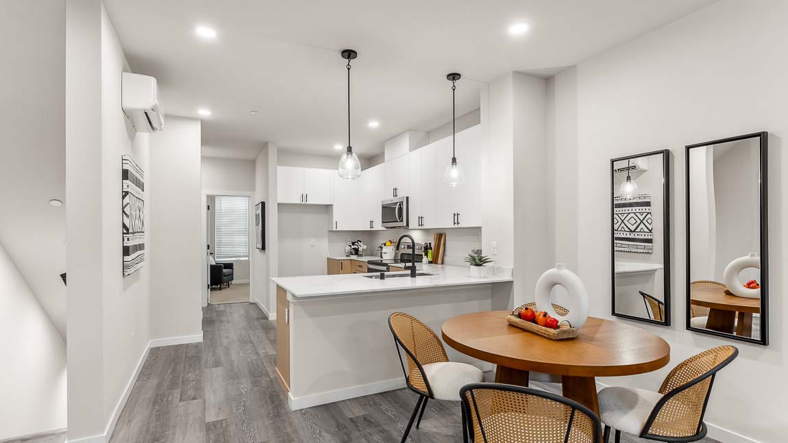 Capri model home dining room with nearby kitchen peninsula featuring undermount kitchen sink and pendant lighting, with peek-a-boo view of stairwell