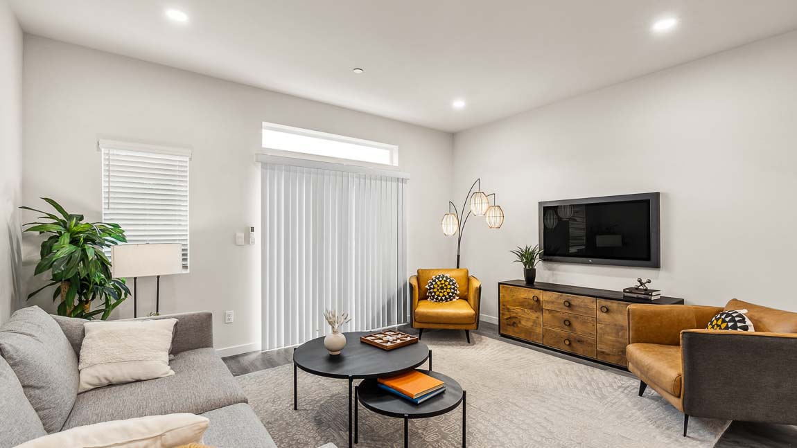 Alternate view of Capri model home living room with bright corner window, slider door access to balcony and transom above for additional natural light