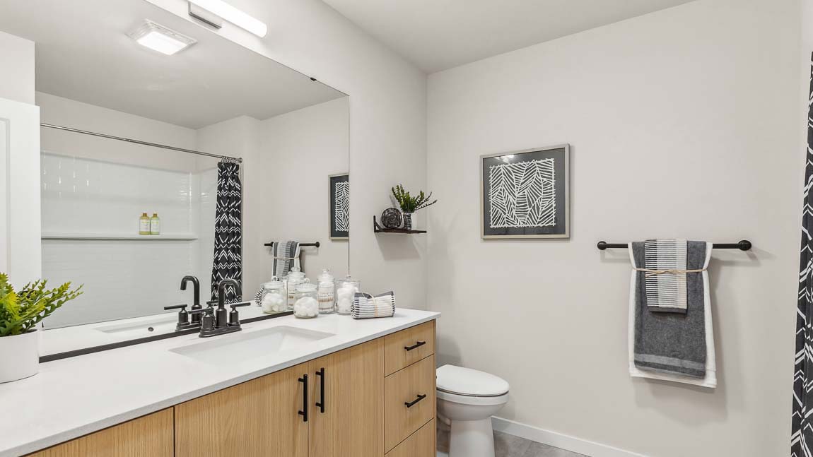 Capri model home upstairs hallway bathroom that provides quartz countertop vanity with undermount sink and tub-shower combo including a built-in shelf